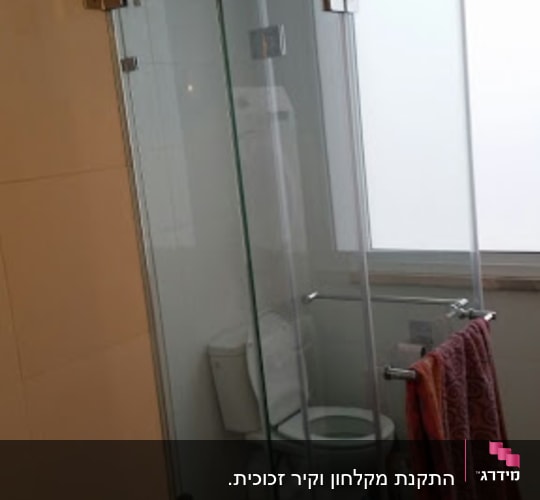 מקלחון זכוכית עם דלתות שקופות ומגבת תלויה